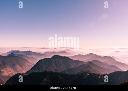 Vista della catena montuosa dell'Himalaya con silhouette visibili attraverso la colorata nebbia dalla cima del percorso di trekking Khalia. La cima Khalia si trova ad un'altitudine di 3500m h. Foto Stock
