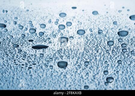 Primo piano goccia acqua su uno sfondo lucido. Immagine con tonalità blu. DOF poco profondo. Foto Stock
