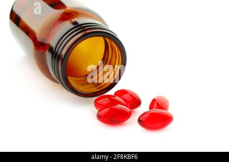 Pillole di vitamina rossa in flaconcino isolato su sfondo bianco Foto Stock