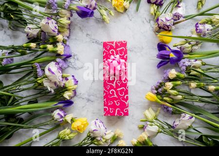 Regalo di festa di primavera creativo. Confezione regalo con decorazioni floreali su rosa. Giorno della mamma, sfondo di primavera Foto Stock