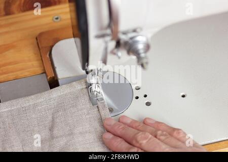 Donna di mezza età mani tela da cucire su macchina da cucire, dall'alto vista dall'alto, artigianato, moda lenta, momenti di vita quotidiana ed eco Foto Stock