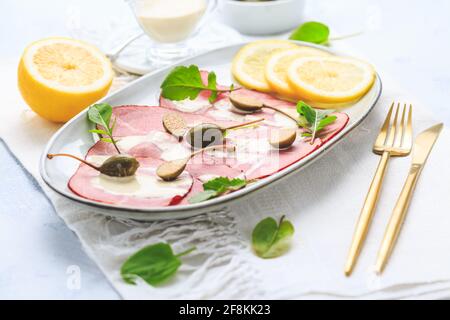 Vitello tonnato - cucina italiana, vitello a fette con salsa di tonno come antipasto con capperi Foto Stock