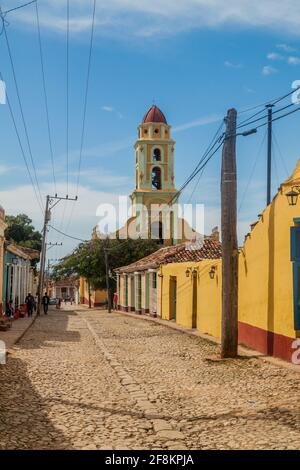 TRINIDAD, CUBA - 8 FEBBRAIO 2016: Vista di una strada acciottolata nel centro di Trinidad, Cuba. Campanile del Museo Nacional de la Lucha Contra Bandidos in Th Foto Stock