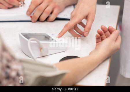 Vista ravvicinata. Misurazione della pressione sanguigna di un paziente in uno studio medico. Medico generico e tirocinante Foto Stock