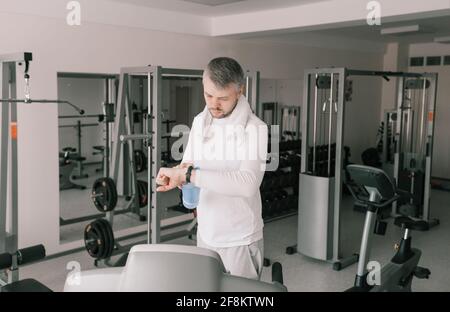 un uomo dopo un allenamento intenso guarda un intelligente guarda Foto Stock