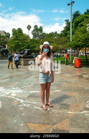 Medellin, Antioquia, Colombia - 6 gennaio 2021: Il turista indossa una maschera e un cappello in Plaza Botero Foto Stock