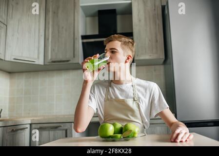 Giovane uomo forte che ha leggero breakfast.Apple succo in cucina. Frutta fresca e cibo sano Foto Stock