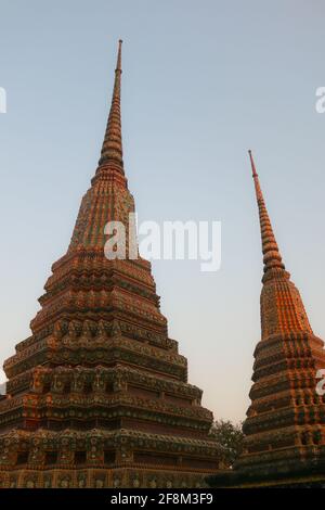 Due stupa buddisti che raggiungono simmetrici il cielo limpido in vista ad angolo basso. Queste pagode fanno parte del Phra Chedi Rai nel complesso del tempio di Wat Pho Buddha. Foto Stock