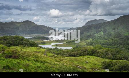 Iconico punto di osservazione irlandese, Ladies View, con laghi multipli, valle verde, foresta e montagne, Killarney, Rink di Kerry, Irlanda Foto Stock