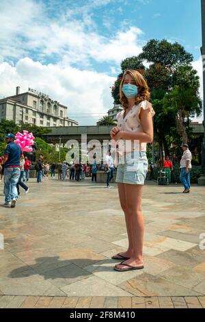 Medellin, Antioquia, Colombia - 6 gennaio 2021: Il turista indossa una maschera e un cappello in Plaza Botero Foto Stock