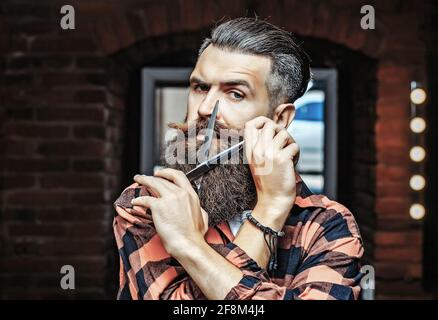 Uomo bearded con forbici. Forbici da barbiere e rasoio dritto, barbiere, tuta. Barbiere d'epoca, rasatura. Ritratto uomo bearded. Vintage Foto Stock