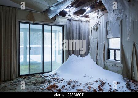 Neve che si è raccolta sotto un soffitto crollato all'interno di una casa. Foto Stock