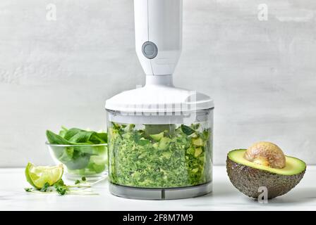 avocado, sedano e spinaci in contenitore trasparente in plastica per preparare un sano frullato da colazione sul tavolo da cucina Foto Stock