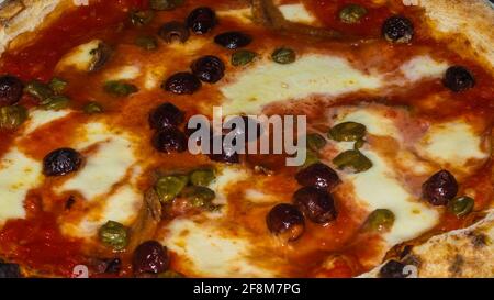 dettaglio di una pizza con pomodoro, mozzarella, olive, capperi e acciughe Foto Stock