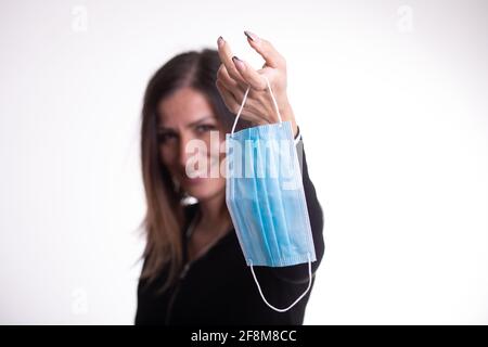 La donna felice toglie la maschera medica protettiva la tiene sul suo dito, gode di vita, aria fresca pulita dopo la pandemia Covid-19, auto-isolamento. Quarantena Foto Stock