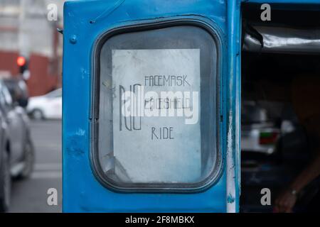 Un cartello sul retro di un veicolo Jeepney, che dichiara che i passeggeri hanno bisogno di una maschera e di uno scudo per entrare nel veicolo, che è un'esigenza per il trasporto pubblico Foto Stock