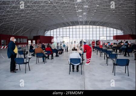 Catanzaro, Italia. 12 Aprile 2021. Un membro della Croce Rossa ha visto aiutare una persona anziana. Al nuovo centro vaccinazioni Covid-19 del Centro Fieristico (Ente Fiera) di Catanzaro Lido, quasi 500 persone di età pari o superiore ai 70 anni, senza particolari patologie, hanno riservato il loro posto per ricevere il vaccino AstraZeneca. I membri della Croce Rossa Italiana e della protezione civile aiutano gli operatori sanitari locali in materia amministrativa e sanitaria per attuare il programma di vaccinazione. (Foto di Valeria Ferraro /SOPA Images/Sipa USA) Credit: Sipa USA/Alamy Live News Foto Stock