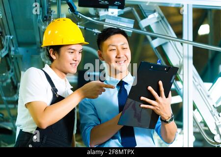 Lavoratore o production manager e proprietario, CEO o controller, guardare su un blocco per appunti in una fabbrica Foto Stock