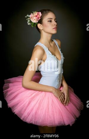 Ballerina giovane con trucco leggero e capelli legati decorati con fiori su  sfondo scuro Foto stock - Alamy