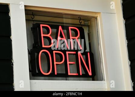 Un cartello al neon illuminato in una finestra a barre. Foto Stock