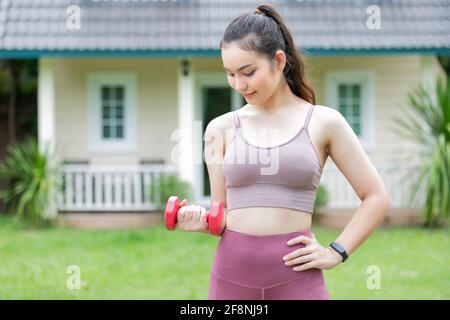 Istruttore di fitness femminile che si esercita con il piccolo manubri sul cortile. Foto Stock