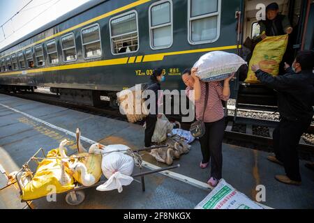 (210415) -- XICHANG, 15 aprile 2021 (Xinhua) -- i peddlers del gruppo etnico Yi scaricano le loro merci dal treno 5633 nella provincia sudoccidentale del Sichuan, 11 aprile 2021. Mentre i moderni treni ad alta velocità passano davanti a nuove stazioni in tutta la Cina, un paio di treni a bassa velocità attraversano ancora le montagne Daliang. I 5633/5634 treni collegano Puxiong e Panzhihua della provincia di Sichuan con una velocità media inferiore a 40 km all'ora. Il viaggio con 26 stazioni in mezzo dura undici ore e quattro minuti, con i prezzi dei biglietti che variano da 2 yuan a 25.5 yuan (circa 0.3-3.9 dollari USA). La s Foto Stock