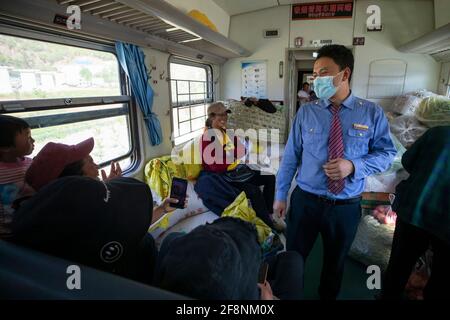 (210415) -- XICHANG, 15 aprile 2021 (Xinhua) -- UN amministratore del treno del gruppo etnico Yi parla ai passeggeri sul treno 5634 nella provincia sudoccidentale del Sichuan, 12 aprile 2021. Mentre i moderni treni ad alta velocità passano davanti a nuove stazioni in tutta la Cina, un paio di treni a bassa velocità attraversano ancora le montagne Daliang. I 5633/5634 treni collegano Puxiong e Panzhihua della provincia di Sichuan con una velocità media inferiore a 40 km all'ora. Il viaggio con 26 stazioni in mezzo dura undici ore e quattro minuti, con i prezzi dei biglietti che variano da 2 yuan a 25.5 yuan (circa 0.3-3.9 dollari USA). Foto Stock