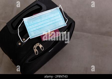Viaggio coronavirus. Valigia con maschera protettiva e passaporto Foto Stock