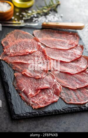 Carpaccio a fette. Carne di manzo cruda su tagliere nero. Foto Stock