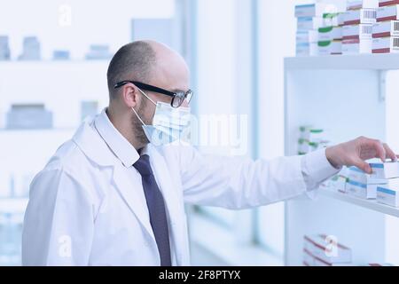 Il farmacista sta lavorando. Uomo che indossa uniforme medica speciale. Situato in Farmacia. Foto Stock