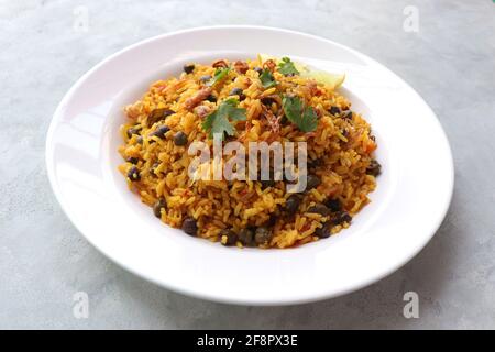 Cucina indiana - ceci Biryani, chole Pulao. Guarnito con cipolla fritta, coriandolo tritato e spicchi di limone. Kala chana biryani. Copia spazio Foto Stock