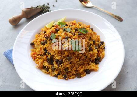 Cucina indiana - ceci Biryani, chole Pulao. Guarnito con cipolla fritta, coriandolo tritato e spicchi di limone. Kala chana biryani. Copia spazio Foto Stock