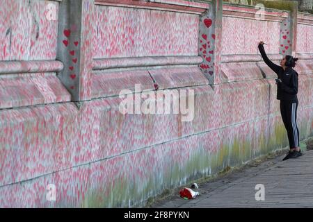 La gente cammina oltre e scrive sul muro commemorativo nazionale del Covid, a Londra il 9 aprile 2021 Foto Stock