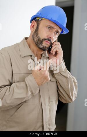 il tecnico parla al telefono e mostra il dito rivolto verso l'alto Foto Stock