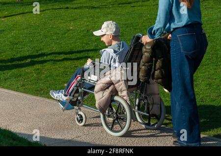 Krasnodar, Russia - Aprile 14 2021: Ragazzo in sedia a rotelle guarda in lontananza in tempo soleggiato. Foto Stock