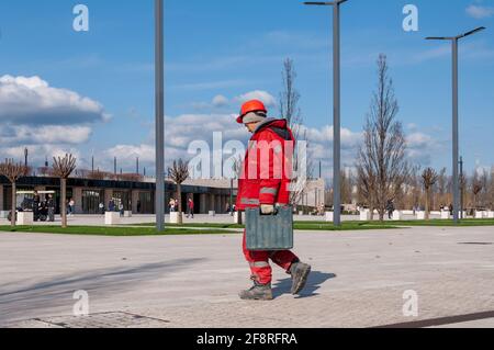 Krasnodar, Russia - Aprile 14 2021: Elettricista in uniforme rossa cammina attraverso il parco da o per lavorare. Foto Stock