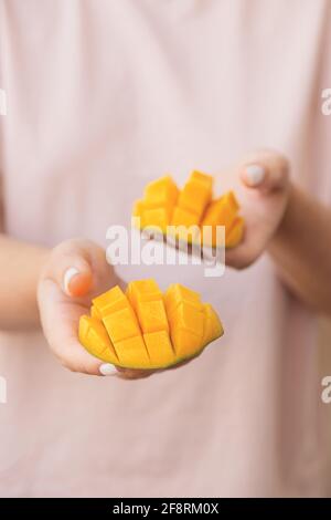 Belle fette di mango tritato in mani femminili. Dolce vegano sano Foto Stock