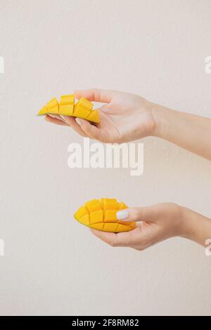 Belle fette di mango tritato in mani femminili. Dolce vegano sano Foto Stock