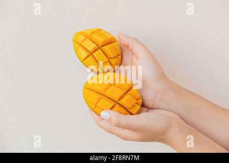 Belle fette di mango tritato in mani femminili. Dolce vegano sano Foto Stock