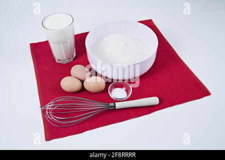 ingredienti per un impasto di pancake su un tappetino rosso Foto Stock