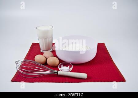 ingredienti per un impasto di pancake su un tappetino rosso Foto Stock