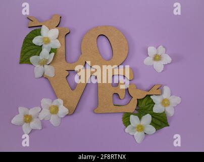 Su uno sfondo lilla, la parola amore è circondata da fiori di anemone bianco. Atmosfera positiva, dichiarazione d'amore, sentimenti romantici. Cartolina. Foto Stock