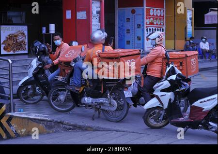 A causa di un recente focolaio di COVID-19 nei mercati e nelle fabbriche di abbigliamento, Il governo cambogiano ha imposto un blocco. Qui i conducenti di consegna di cibo sulle motociclette hanno un incontro improvvisato su come ottenere il loro cibo attraverso i posti di controllo della polizia e blocchi stradali. Molti cambogiani sono in quarantena e non sono autorizzati a lasciare la loro strada per fare shopping durante la pandemia del coronavirus. Stueng Meanchey, Phnom Penh, Cambogia. 15 aprile 2021. © Kraig Lieb Foto Stock