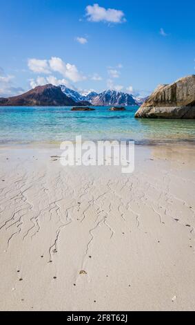 Spiaggia di Haukland o Hauklandstranda, Vestvagoy, isole Lofoten, Norvegia. Bellissima spiaggia sabbiosa con rocce, vista sulle montagne e acqua blu. Nessuna gente. Foto Stock