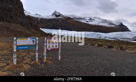 Cartelli segnaletici accanto al sentiero escursionistico al ghiacciaio Svinafellsjokull nel Parco Nazionale Vatnajökull nella stagione invernale con aspre montagne innevate. Foto Stock