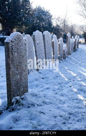 una fila di vecchie lapidi ricoperte di neve in un cantiere Foto Stock