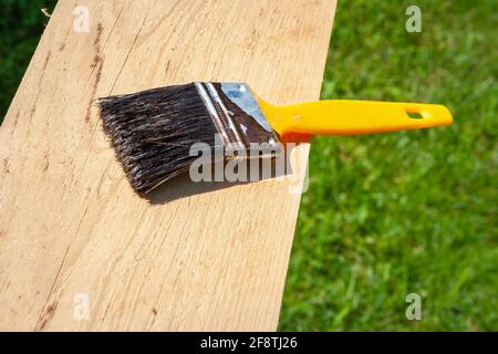 Pennello usato con manico giallo giacente su un legno tavola in giardino Foto Stock
