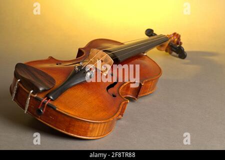 Germania. 04th Apr 2021. Un vecchio violino con lievi graffi e danni giace su uno sfondo neutro, grigio, giallo-illuminato. | utilizzo in tutto il mondo credito: dpa/Alamy Live News Foto Stock