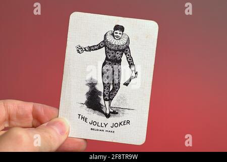 Germania. 09 aprile 2021. La carta da gioco il Jolly Joker da un vecchio gioco di carte, mano francese, tenuto da una mano in un sanguinamento su uno sfondo rosso. | utilizzo in tutto il mondo credito: dpa/Alamy Live News Foto Stock