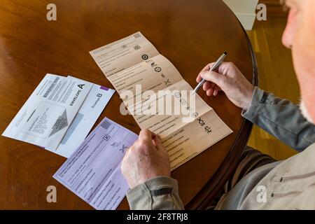 East Lothian, Scozia, Regno Unito, 15 aprile 2021. I voti postali arrivano per le elezioni scozzesi: I residenti della contea possono votare per l'MSP della Lotia orientale e la regione del sud della Scozia. I candidati per il primo sono Euan Davidson (liberali democratici scozzesi), Craig Hoy (conservatori scozzesi e unionisti), Paul McLennan (SNP) e Martin Whitfield (laburisti scozzesi ed ex deputato che ha perso nel 2019 a Kenny MacAskill che sta per Alba). La Lista Regionale comprende 16 parti. Un uomo considera chi votare per il voto sulla scheda elettorale Foto Stock